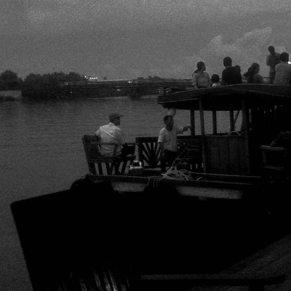 A monochrome photo of men on a boat on a river